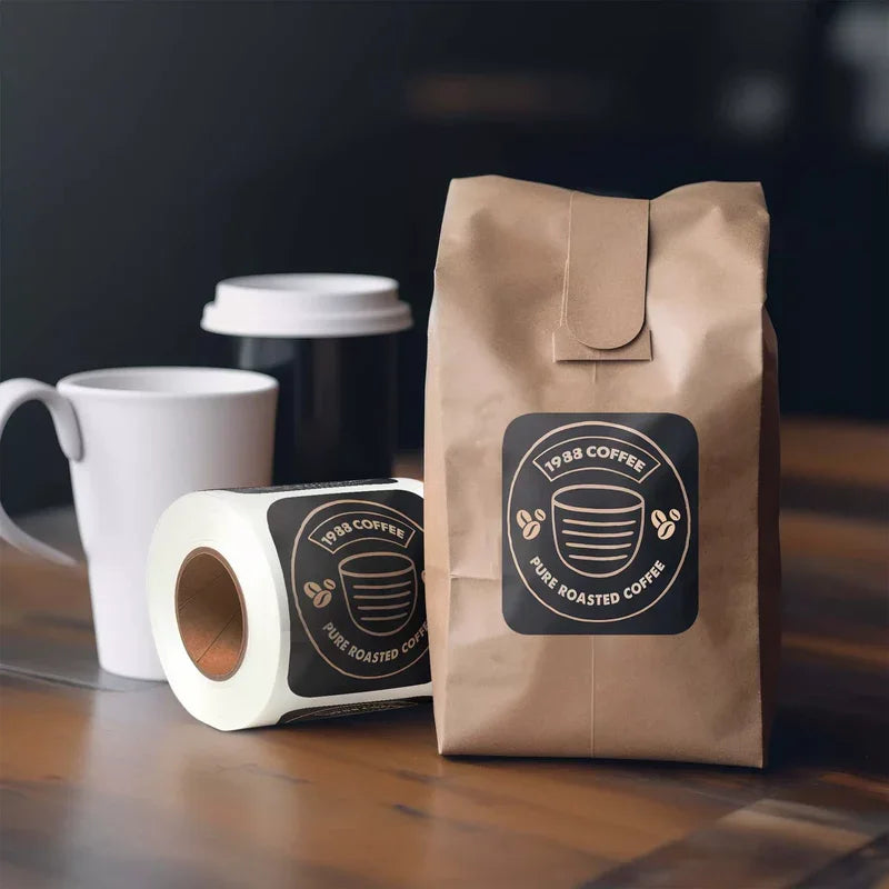 Square Labels with rounded corners on coffee packaging and cup, featuring black and beige branded design on wooden surface