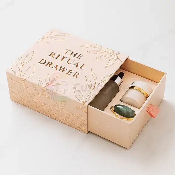 Custom Slide-Out Drawer Boxes | Luxury Rigid Packaging for Gifts & Cosmetics featuring blush pink box with gold leaf design and cosmetic items inside