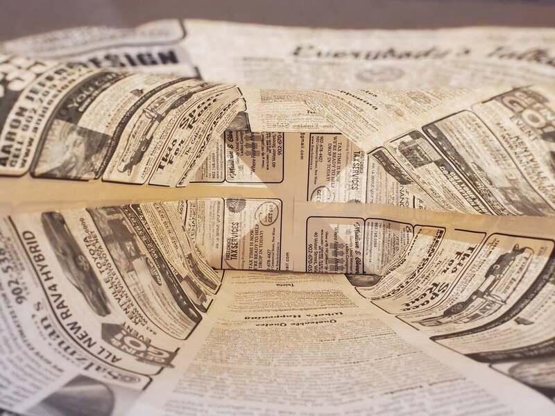 Eco-friendly recycled paper bag with newspaper print, sustainable packaging by Greenii Inc.