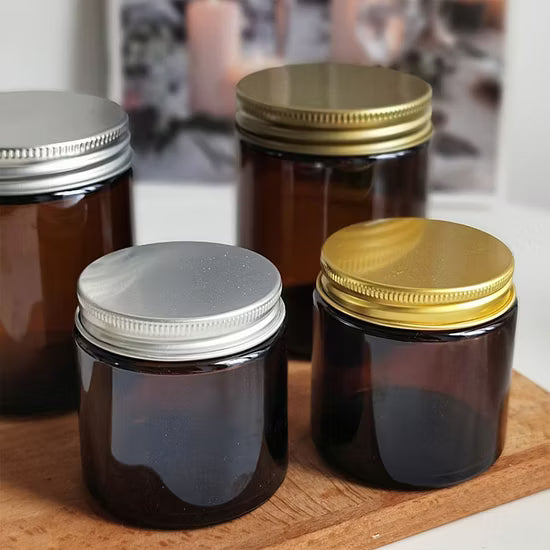 Empty Candle Jars | Wholesale Glass Containers | Eco Friendly Candle Packaging with amber jars and silver and gold metal lids on wooden surface